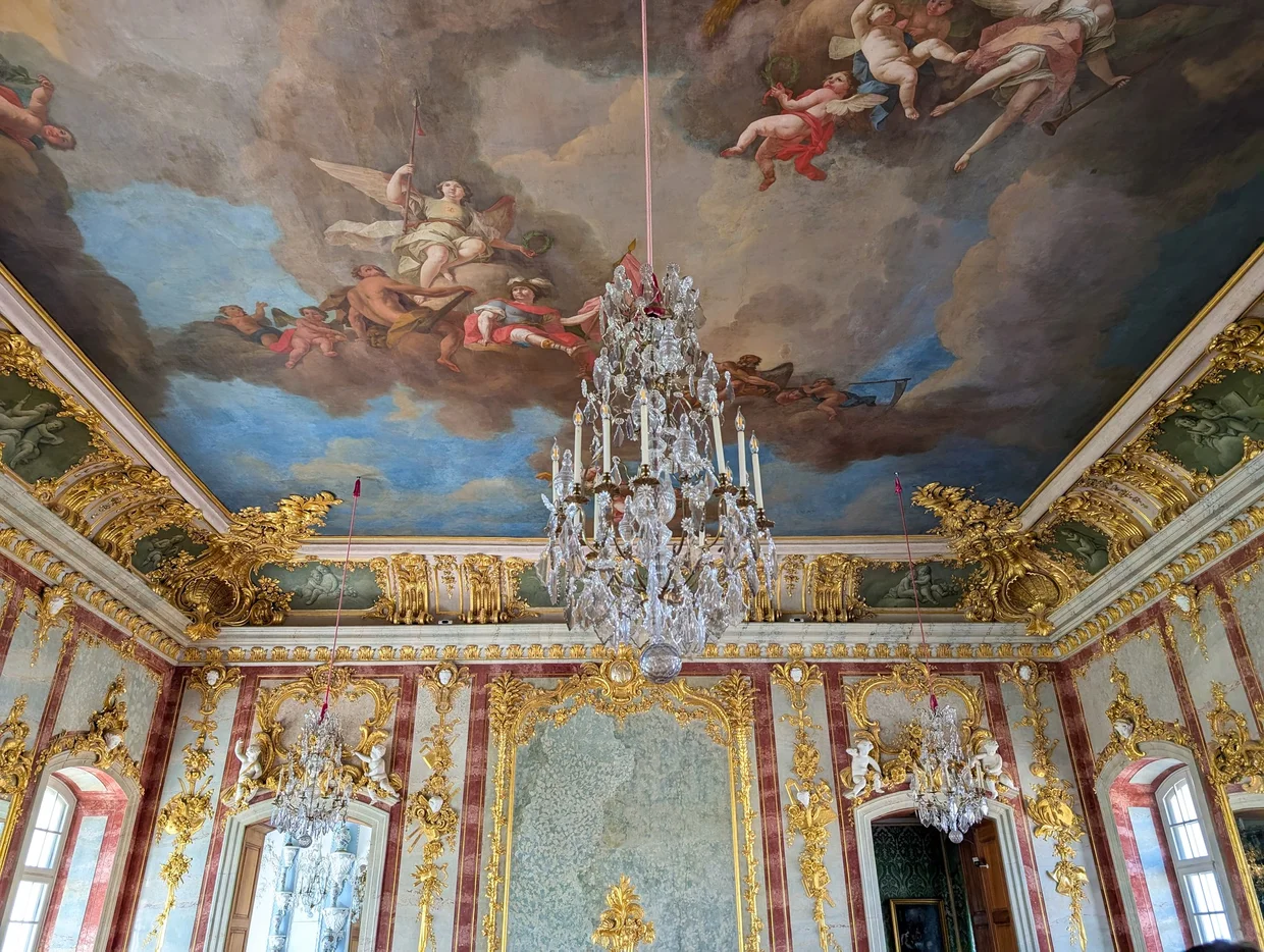 Ornate gilded hall with chandelier and painted ceiling inside Rundāle Palace