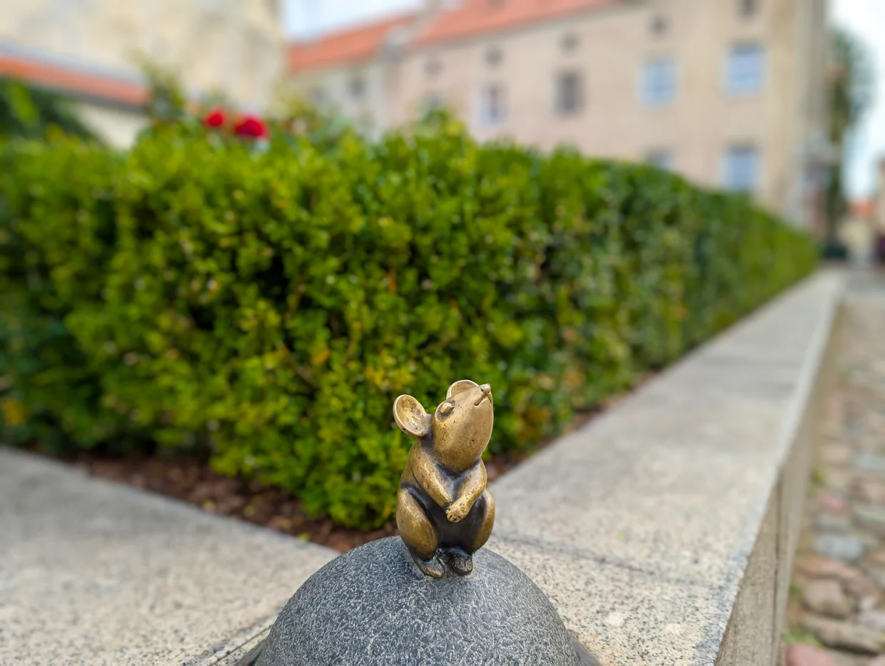 The small bronze "wishing mouse" sculpture on a low wall