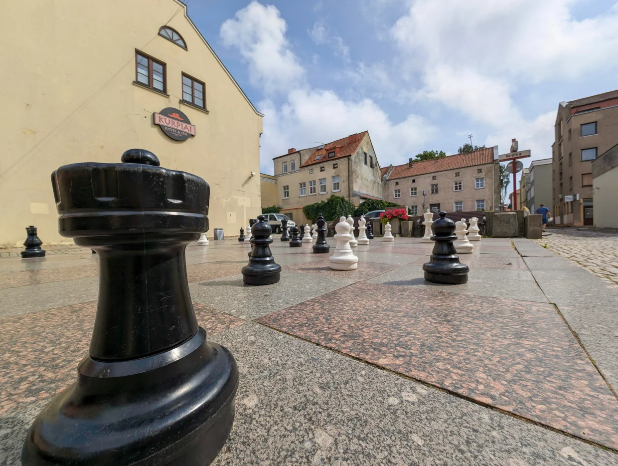 Giant outdoor chess pieces on a painted board in a Klaipėda square
