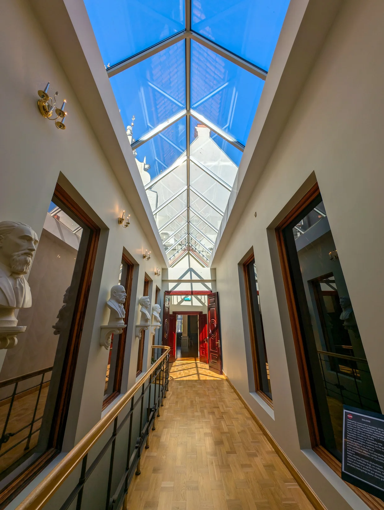 A corridor with busts along the wall and a glass ceiling above