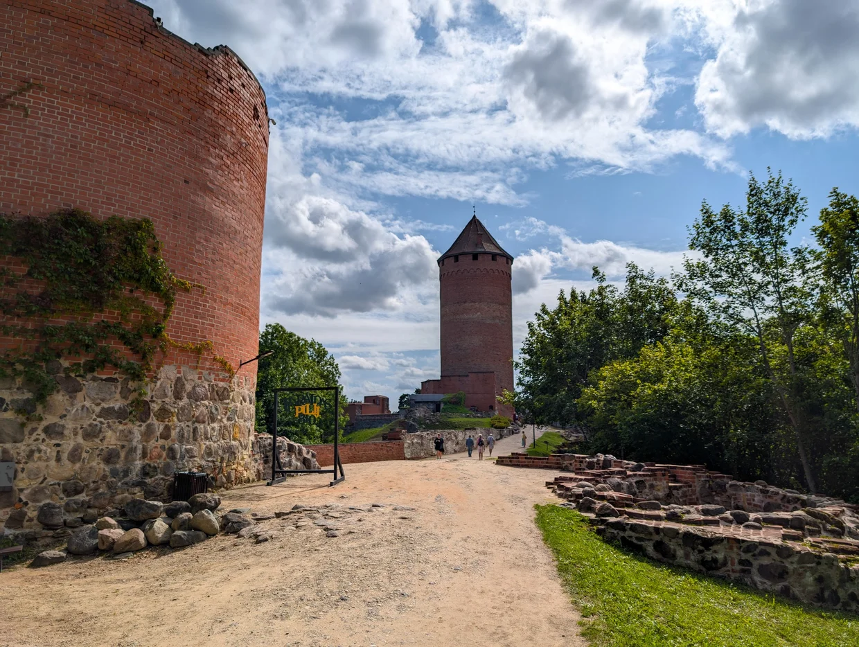 Red brick Turaida Castle with stone entrance and ruins in the foreground