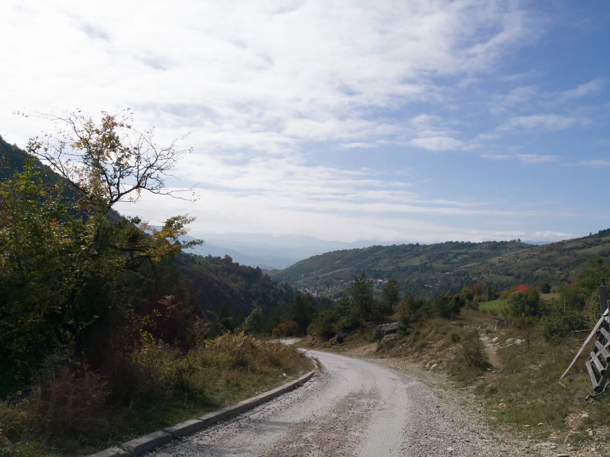 Winding mountain road descending through green hills and villages