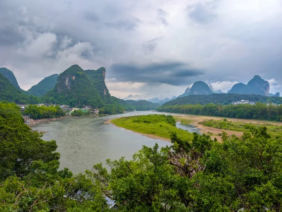 Li River bending through karst mountains under dramatic storm clouds