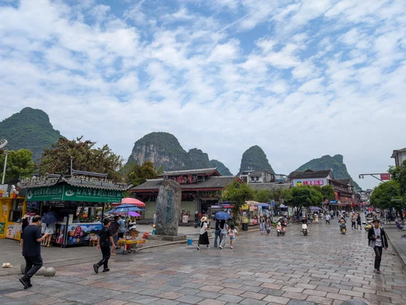 Yangshuo town square with shops and karst mountain peaks in the background
