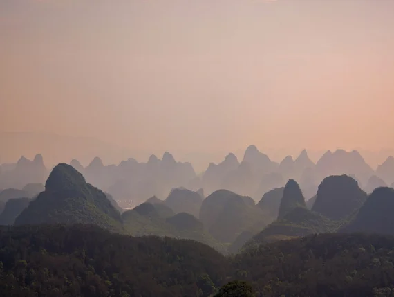 Guilin karst peaks layered in mist at sunset with warm golden light