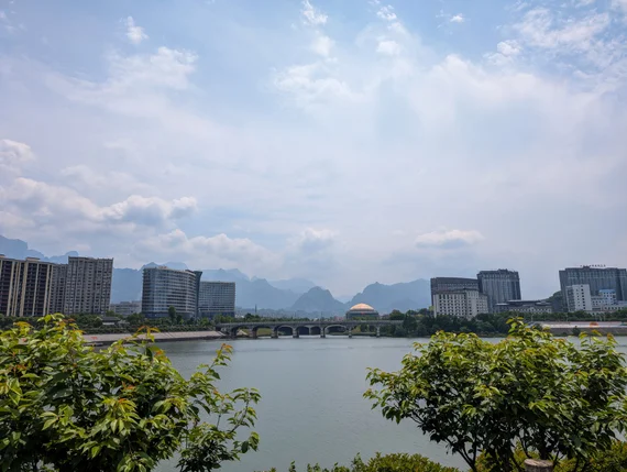 Guilin city skyline across a river with karst mountains in the haze