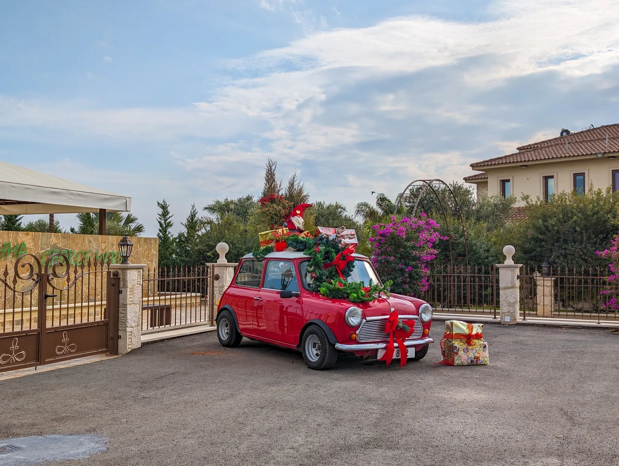 Red vintage Mini decorated with Christmas ornaments in front of a Cypriot villa