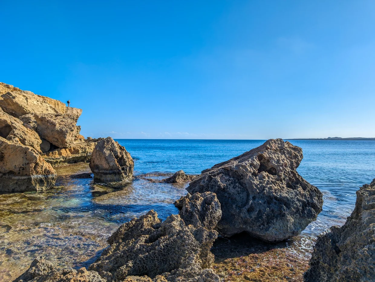 Rocky shoreline with weathered boulders and calm Mediterranean sea