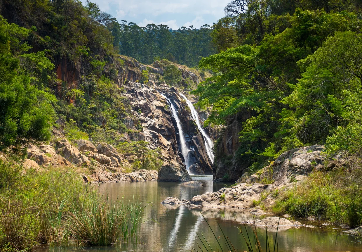Mantenga Falls cascading over rocky cliffs into a pool surrounded by green forest