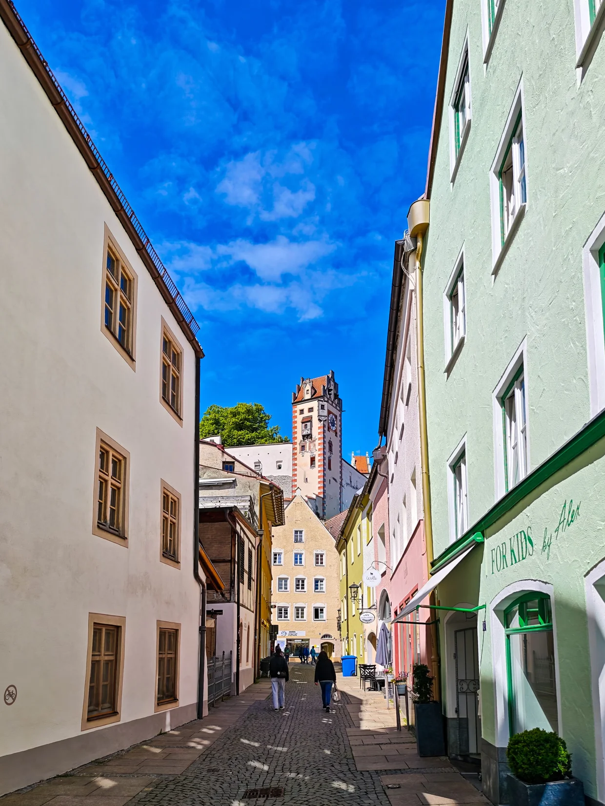 An alley framing the Hohes Schloss tower in the distance