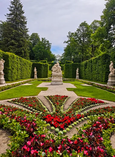 A hedged garden room with statues and flower beds