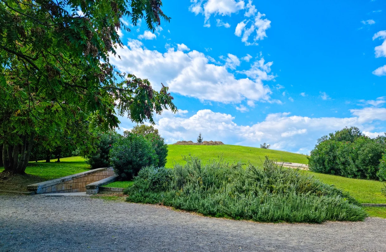 Grassy burial tumulus of Vergina, a gentle green dome rising above a park