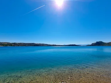 Lake Vouliagmeni with glass-clear water and sun flare