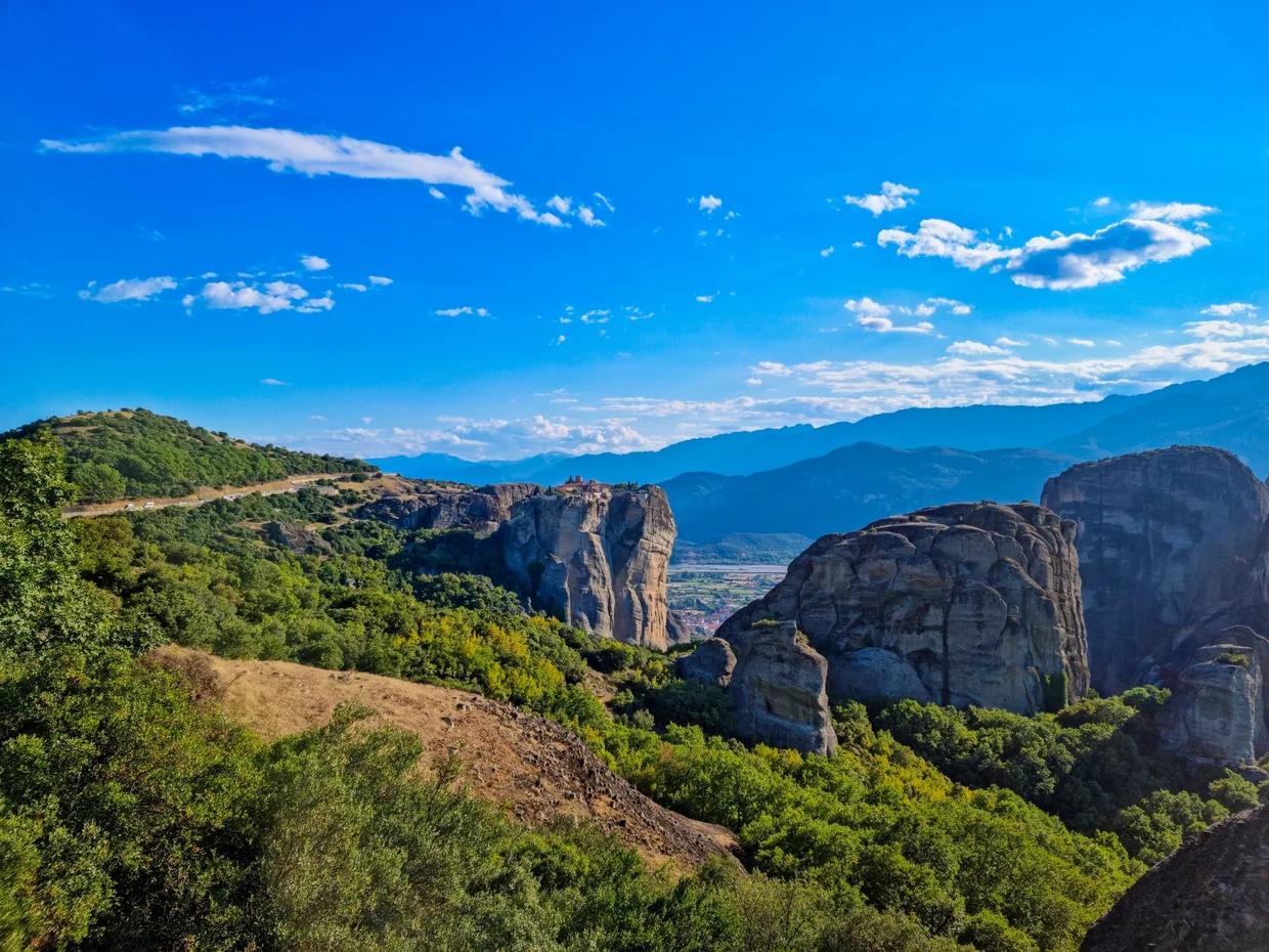 Panoramic view of Meteora rock formations with a small monastery perched on top