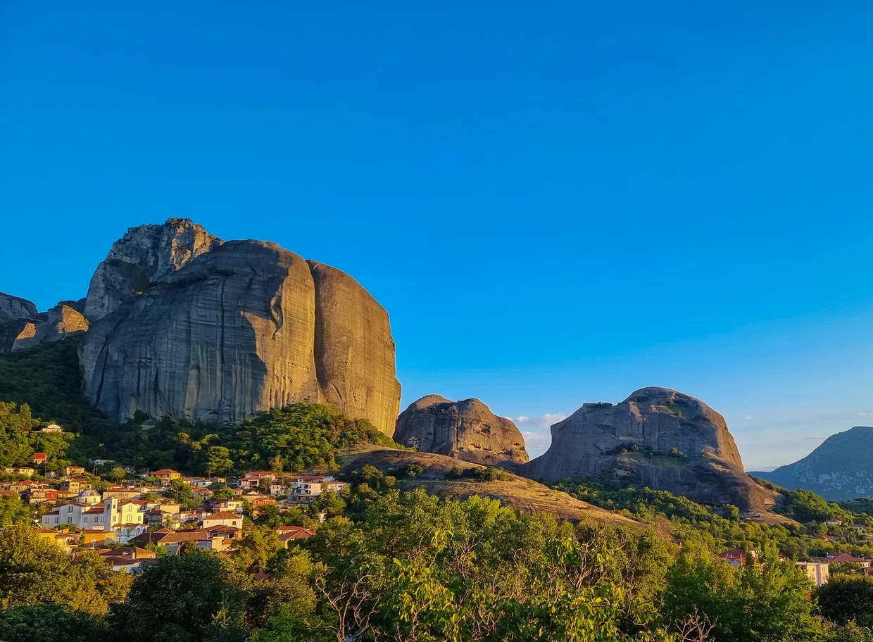 Meteora rocks at golden hour with a small monastery on a distant pillar