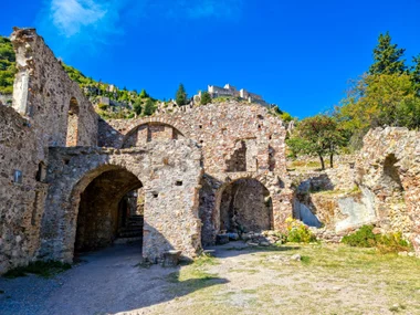 Ruined Byzantine buildings of Mystras with a castle visible on the hill above