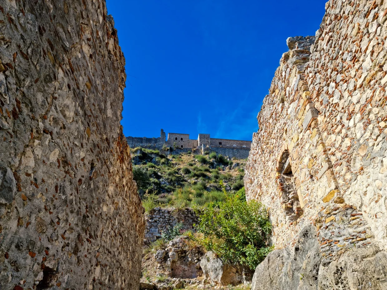 Stone walls and ruins with fortress visible above