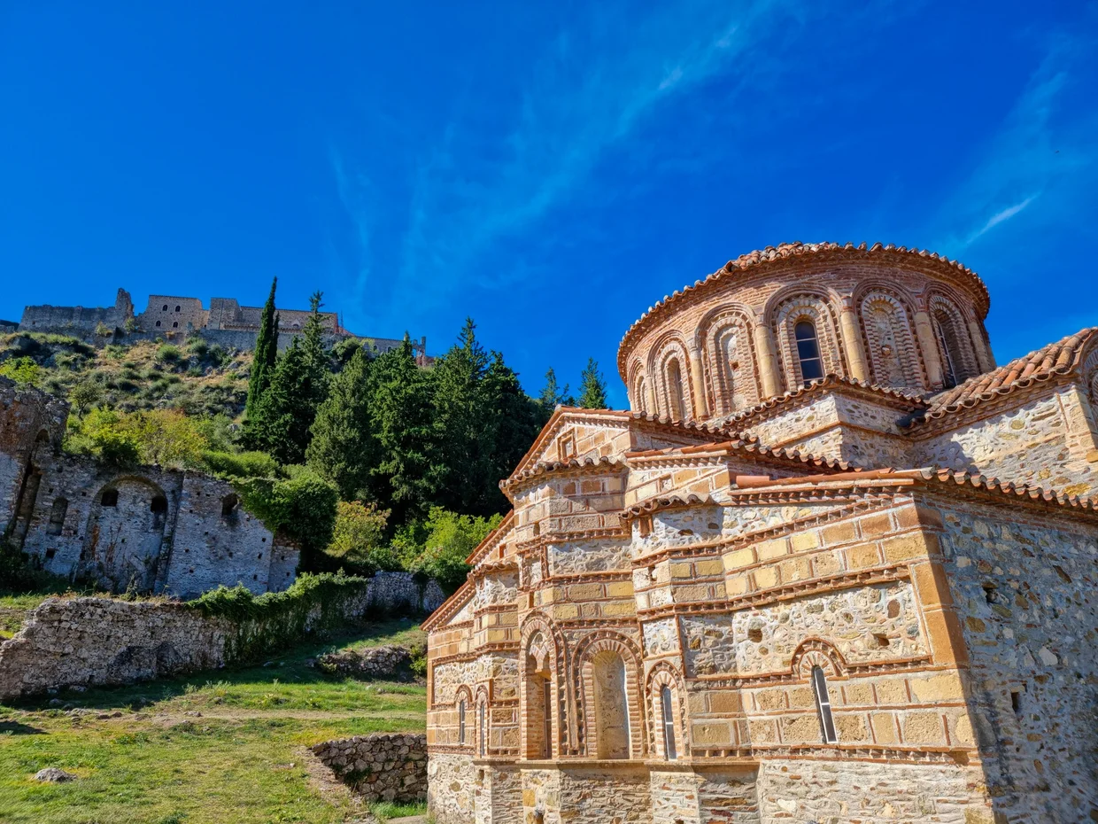 Byzantine church with red tile roof and fortress on the hill behind