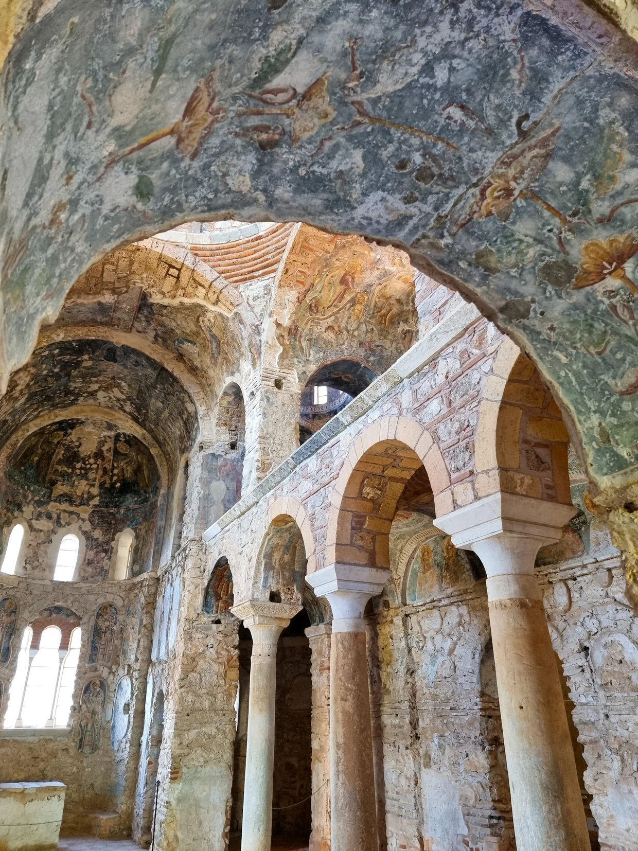 Interior of a Byzantine church with faded frescoes on domed arches and columns