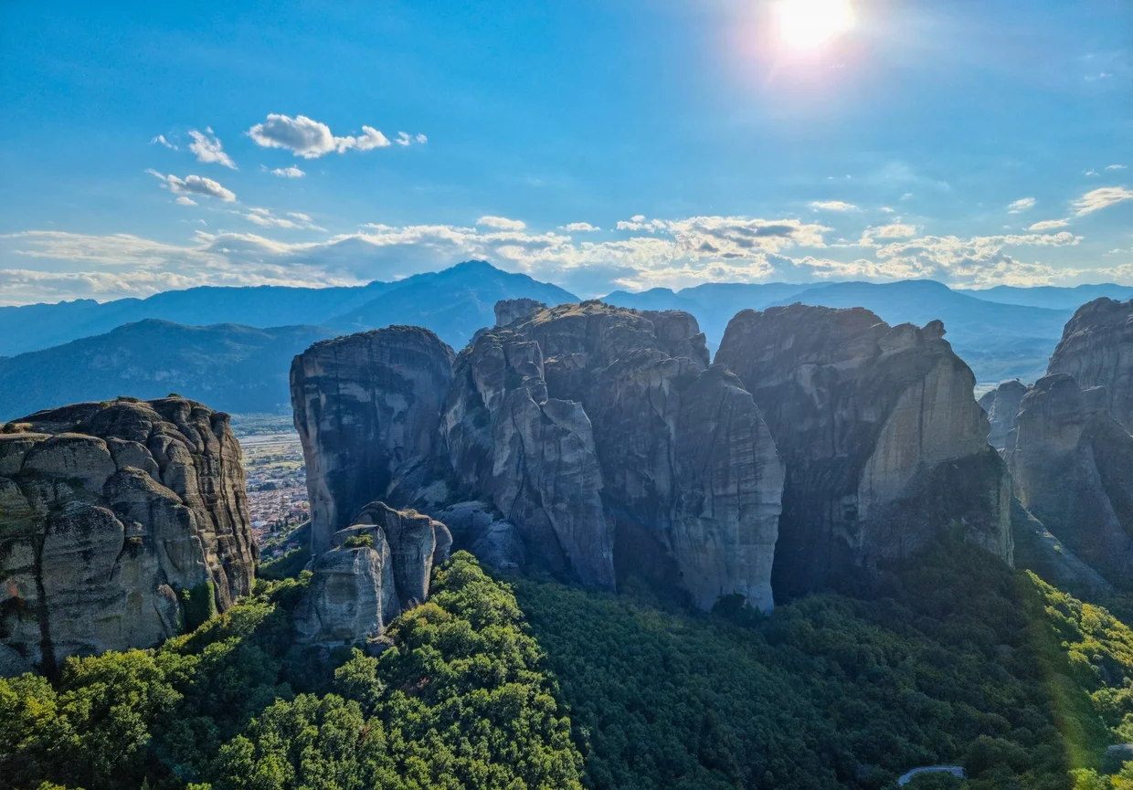 Meteora rock pillars with sun breaking through clouds