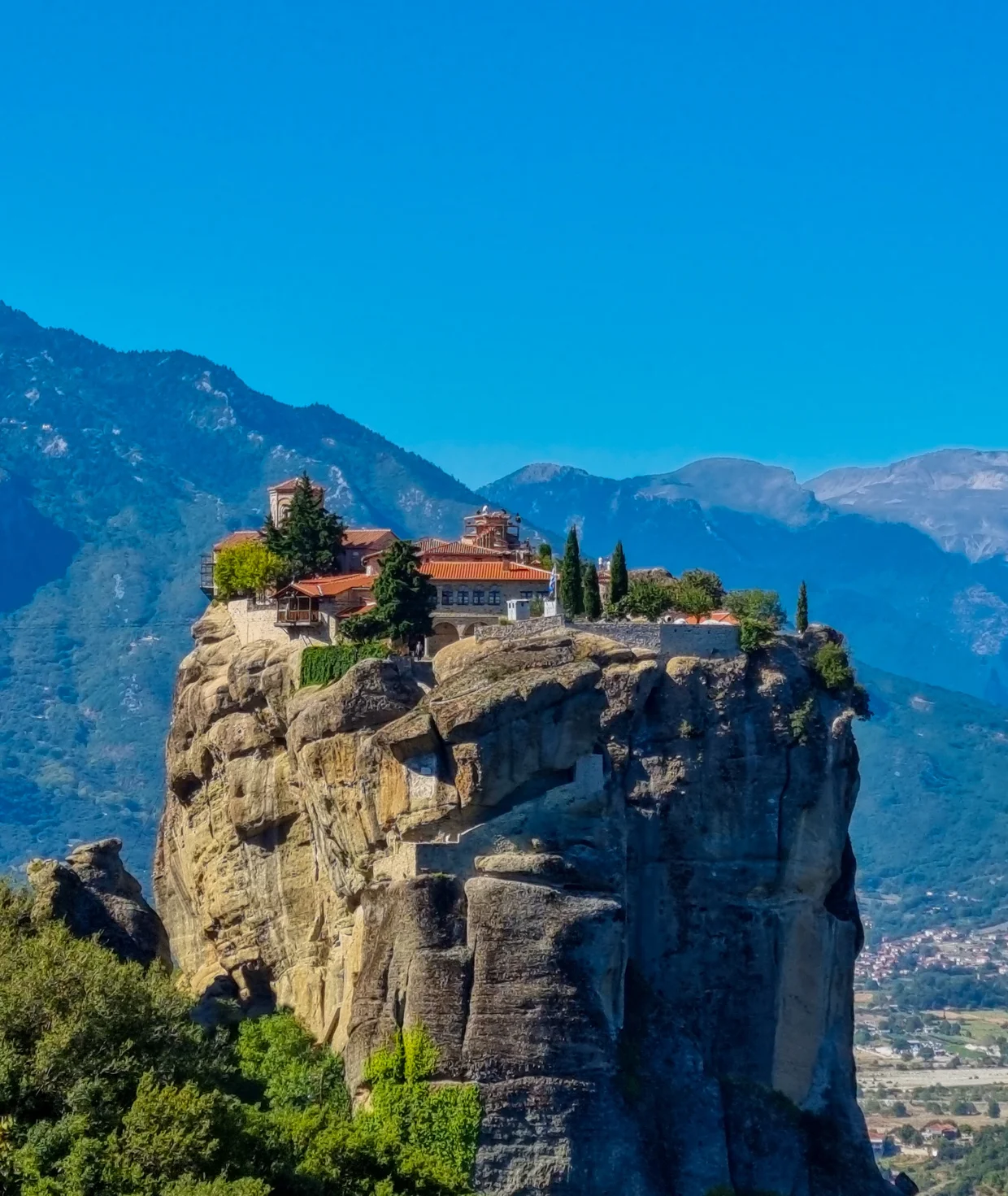 Holy Trinity Monastery on a sheer rock spike, mountains in the background