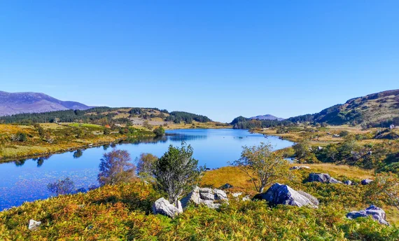 Lake surrounded by autumn-colored hills and rocky shores