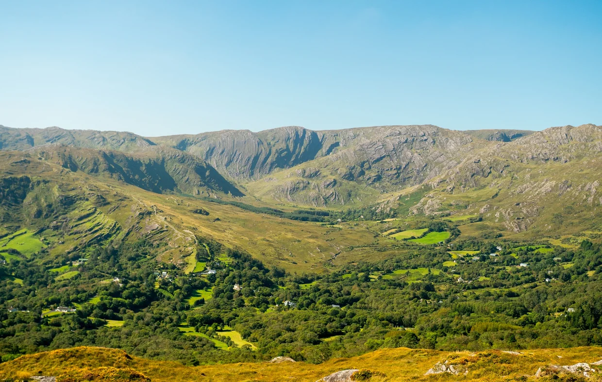 Sweeping green valley with dramatic mountain ridges in the background