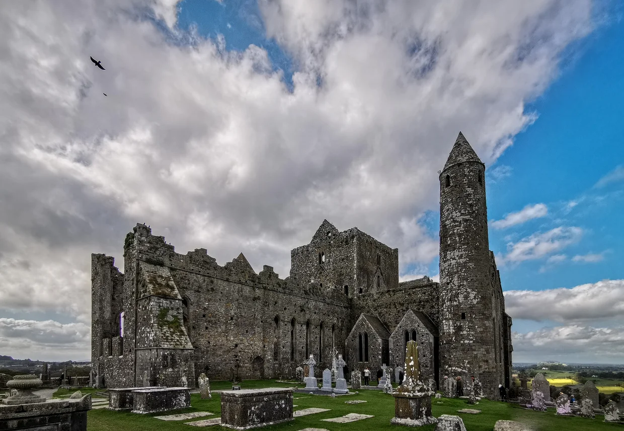 Rock of Cashel exterior with round tower and cathedral ruins under dramatic clouds