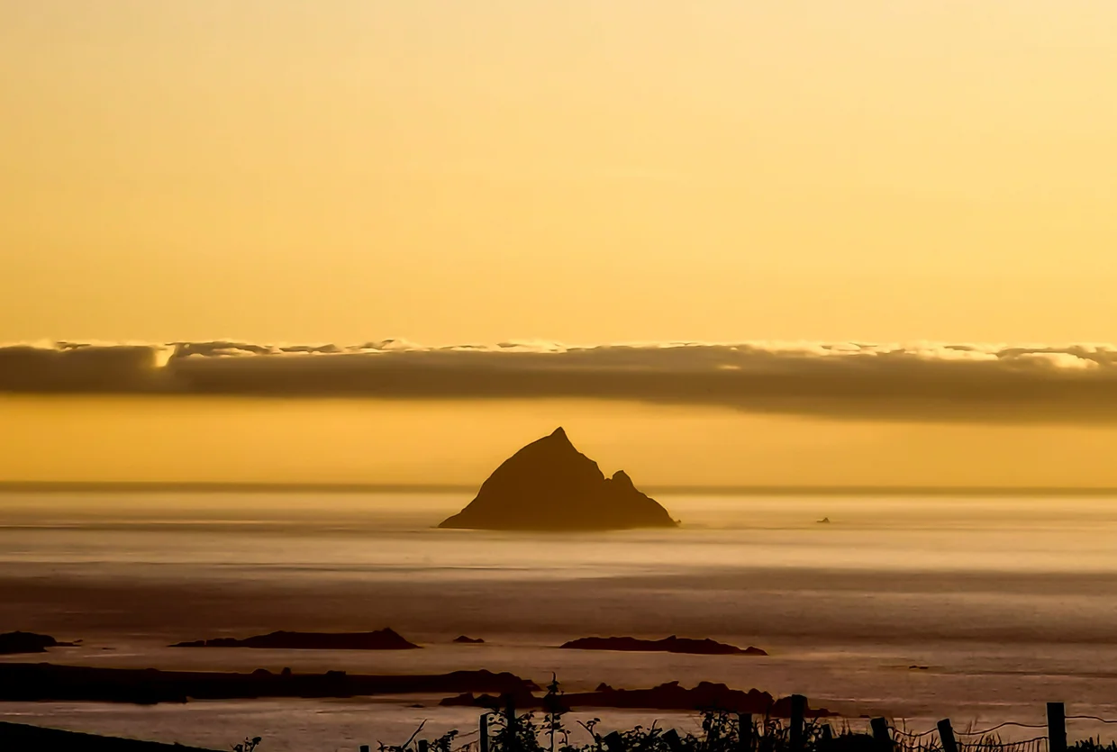 Skellig Michael silhouetted against a golden sunset sky