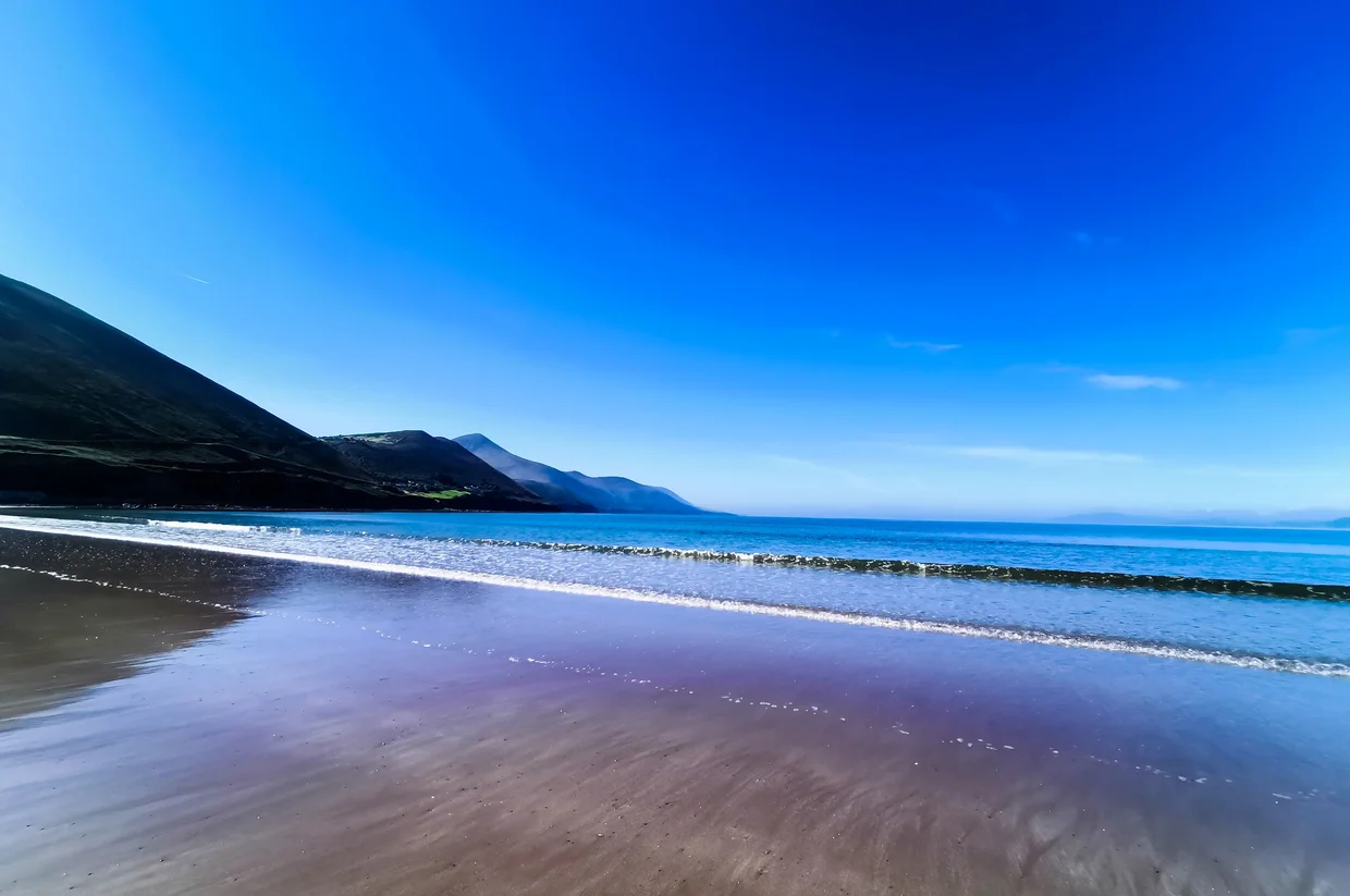 Beach with mountains reflected in the wet sand