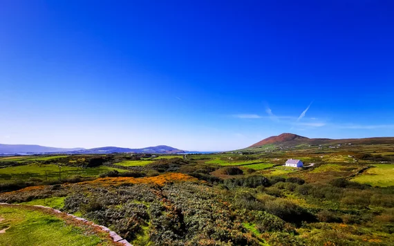 Rolling green countryside with scattered farmhouses and mountains