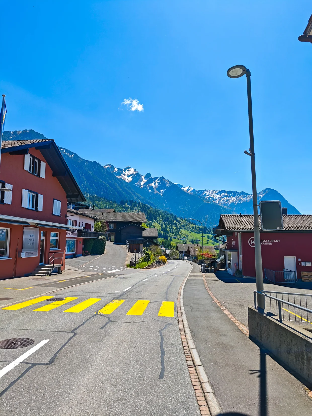 Empty main road through Triesenberg with snow-capped peaks ahead