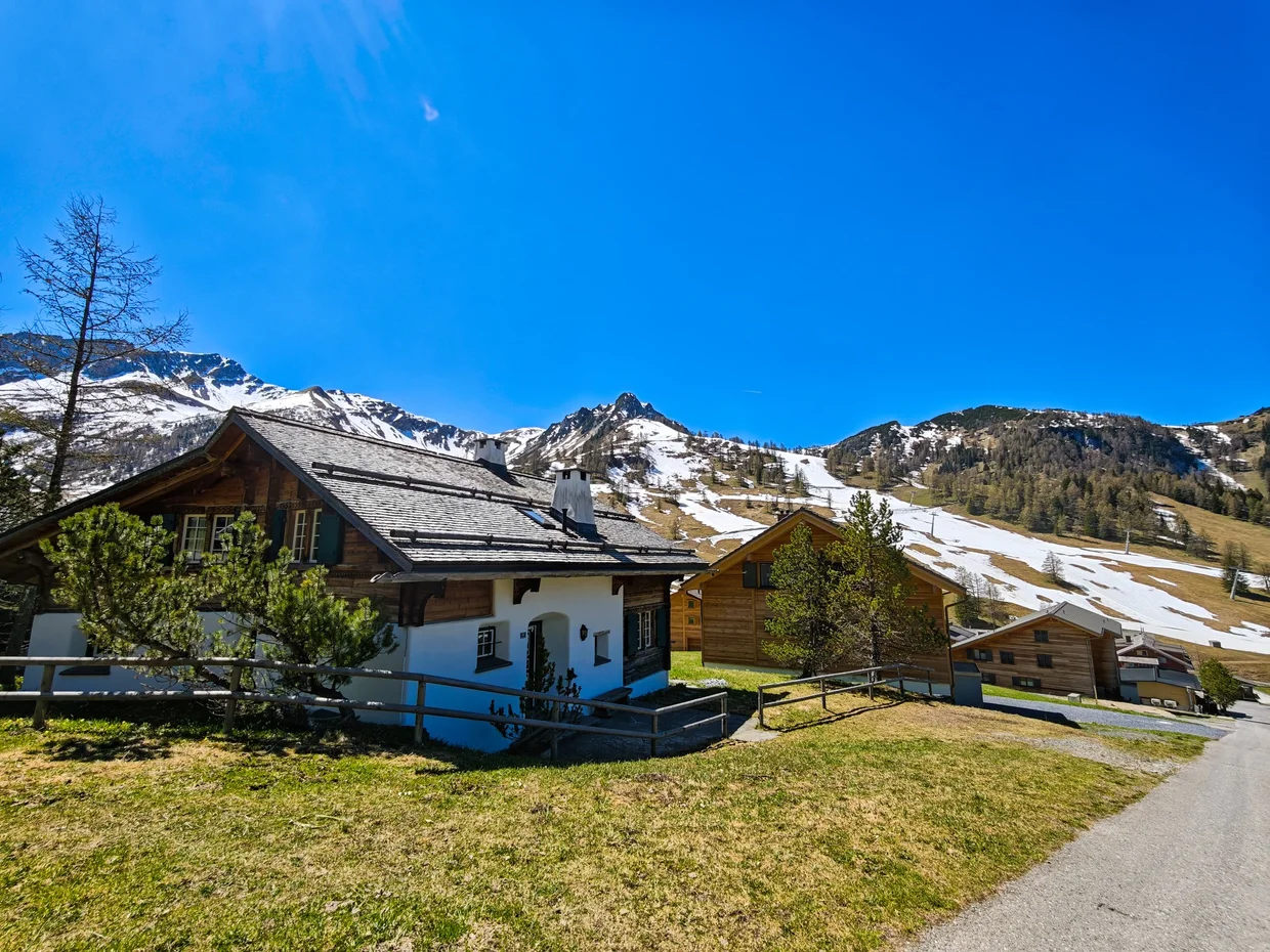 Wooden chalet with a snow-capped peak directly behind it