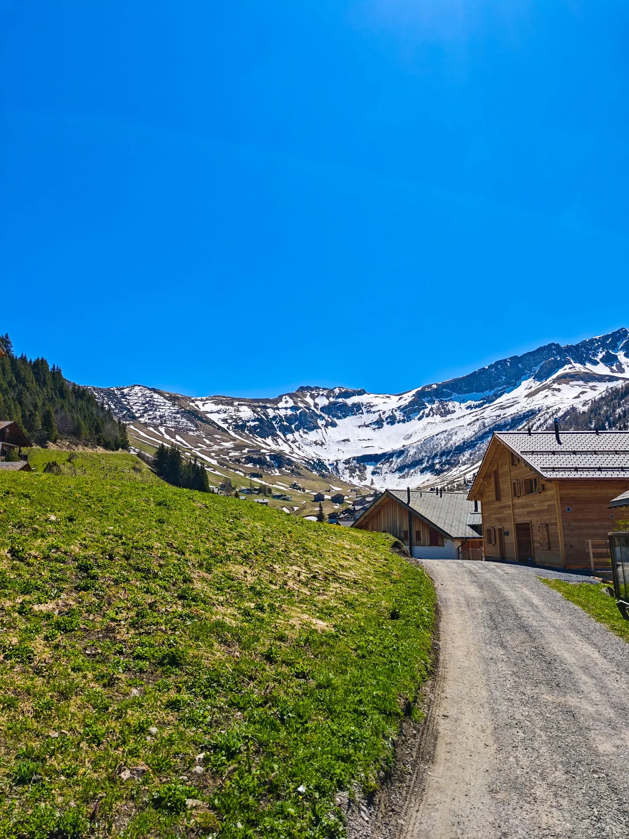 Path through Malbun's wooden houses with the high peaks beyond