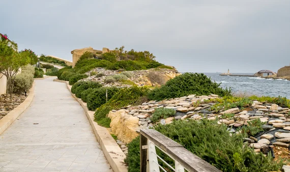 Coastal walking path with Mediterranean scrub and a watchtower