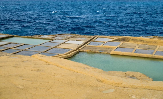 Salt pans with rectangular pools and deep blue sea behind