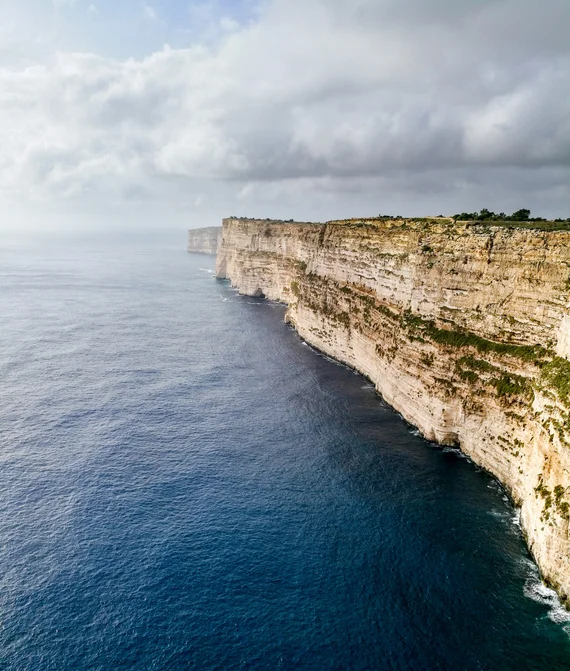 Sheer limestone sea cliffs dropping into deep blue water
