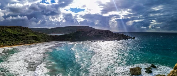 Bay with turquoise water and dramatic sun rays through clouds
