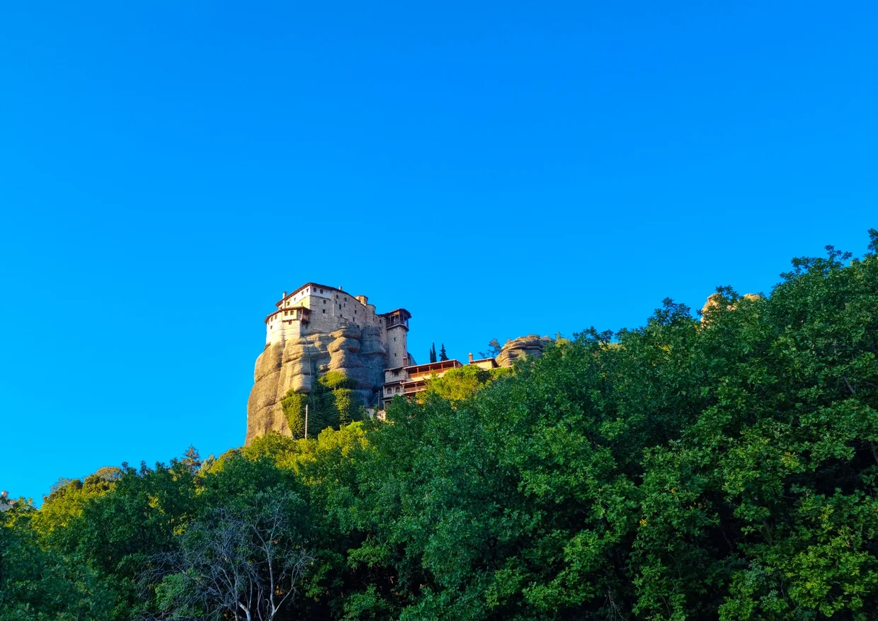 Small Meteora monastery on a rock pillar in golden evening light