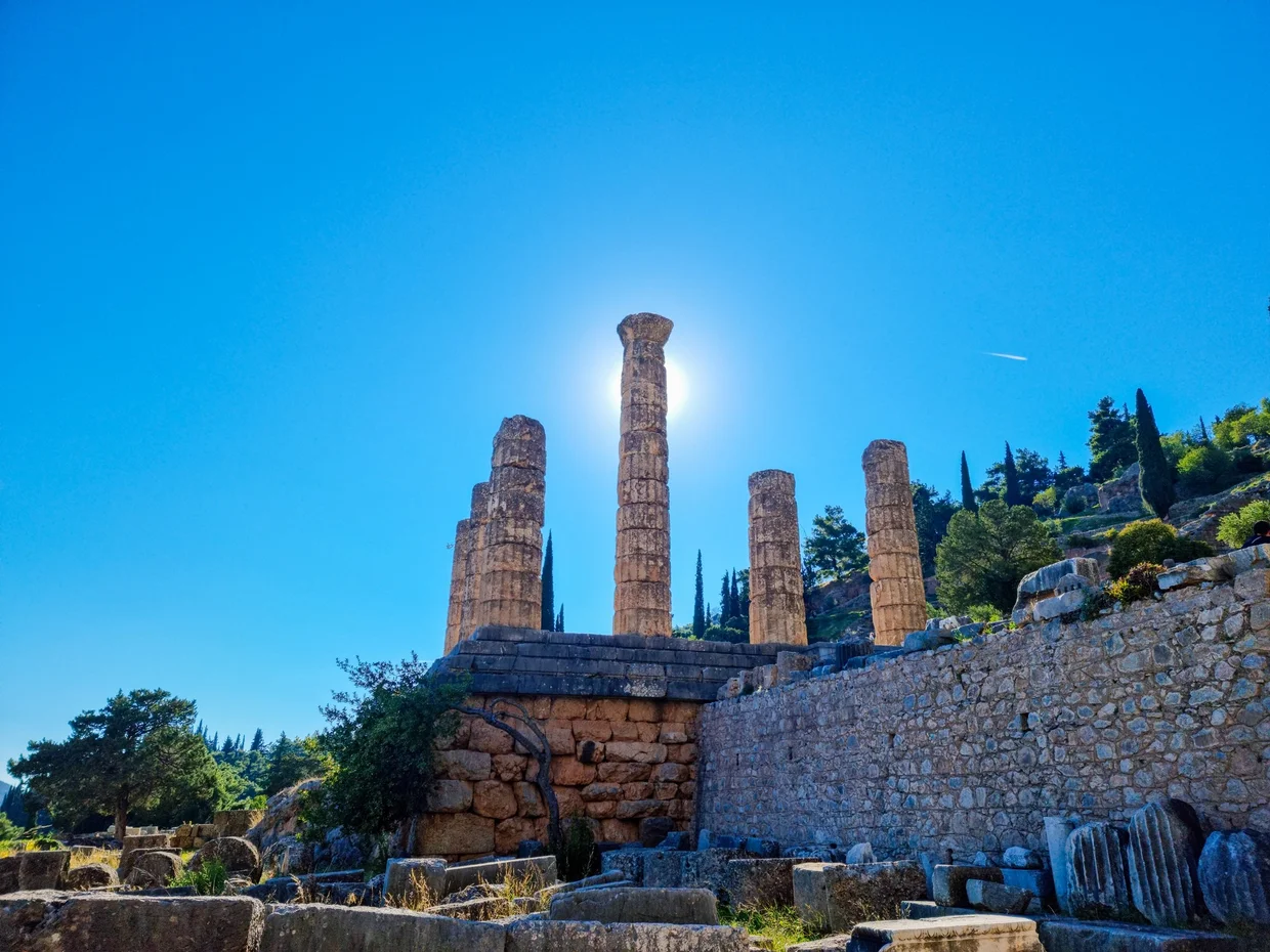 Temple of Apollo at Delphi with sun flaring behind standing columns
