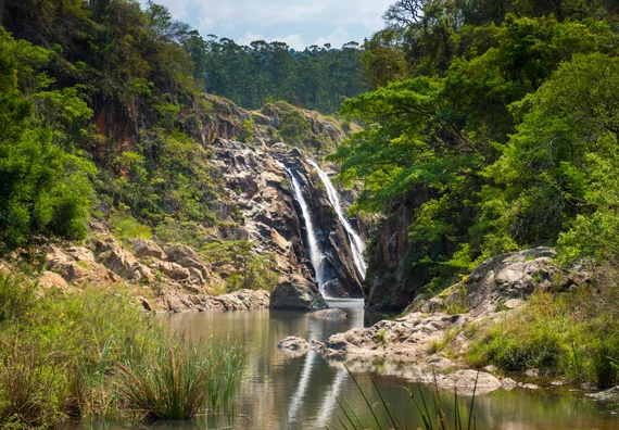 Mantenga Falls cascading over rocks into a pool surrounded by green vegetation