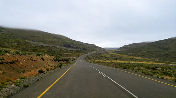 Paved mountain road winding through misty Lesotho highlands