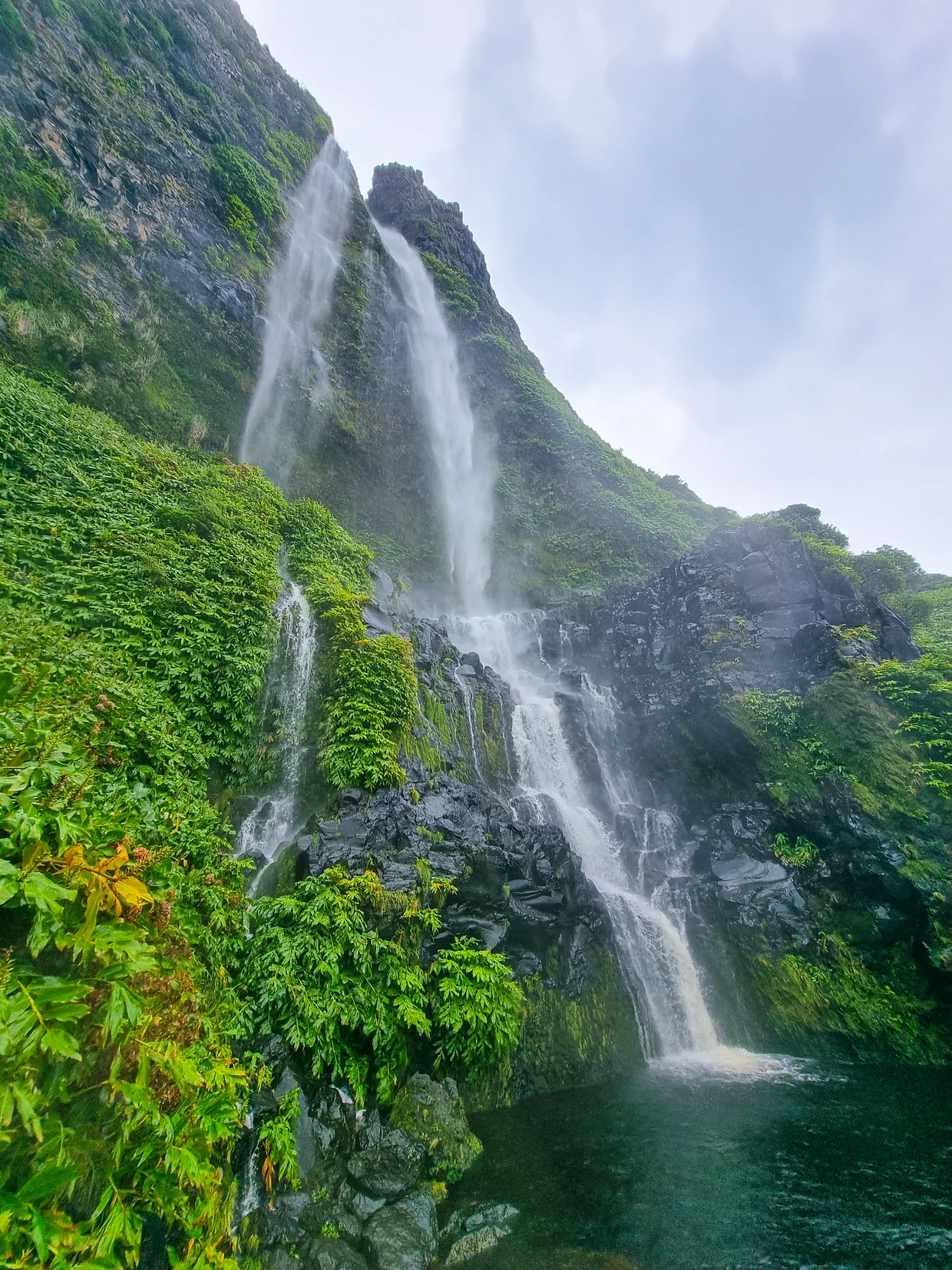 Waterfall crashing into a turquoise pool surrounded by mossy cliffs