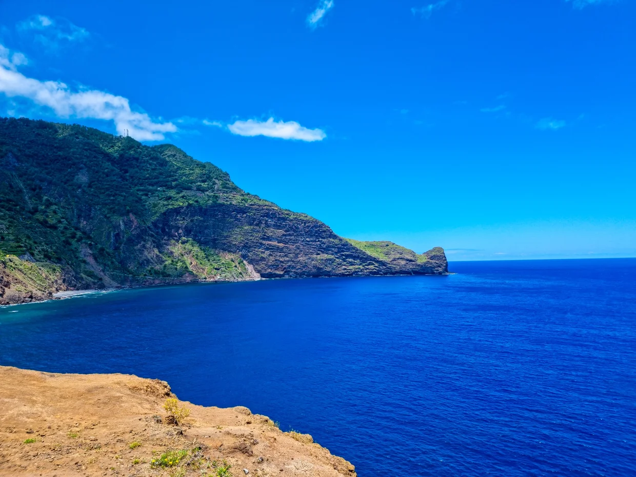 Coastal bay with green mountain headland and deep blue water