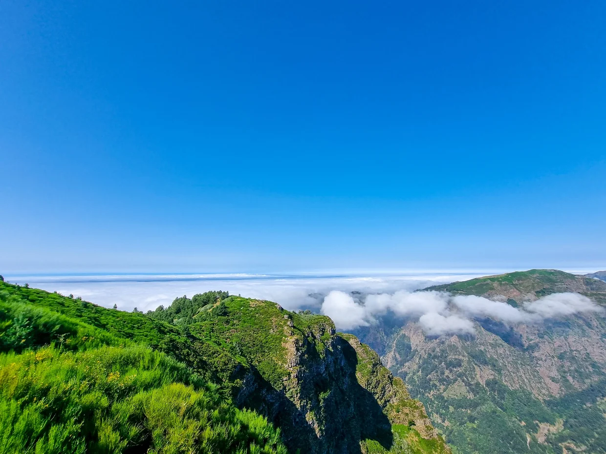 Above the cloud layer, green ridges poking through, the Atlantic visible below