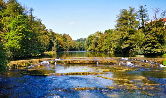 Low river weir with trees on both sides
