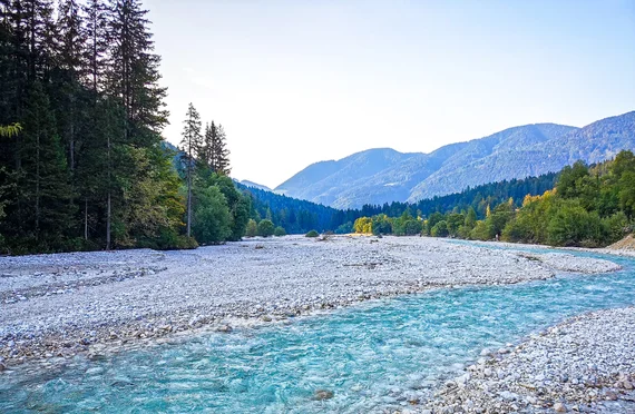 Wide braided turquoise river with mountains beyond