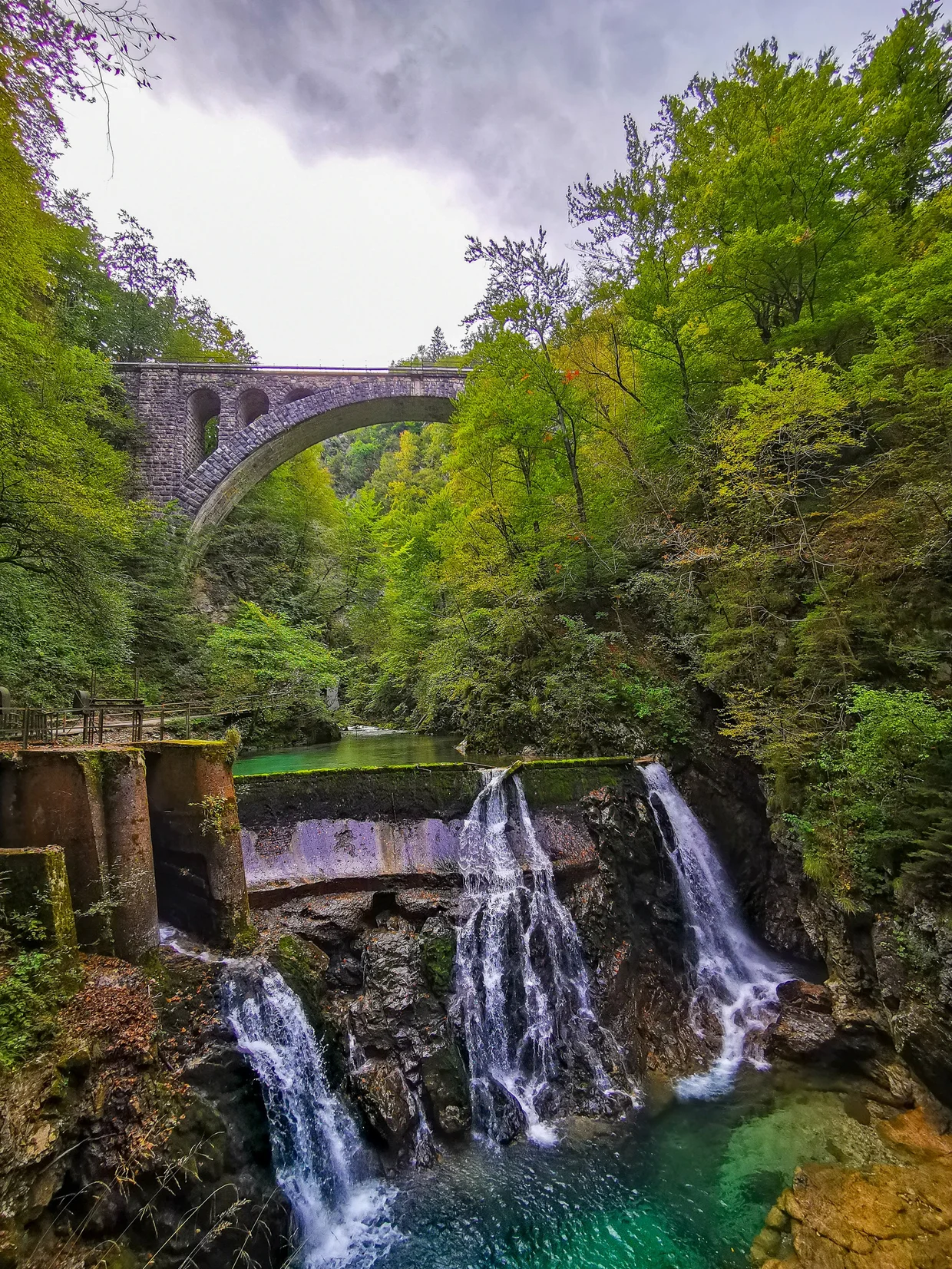 Waterfall and pool with a stone bridge above