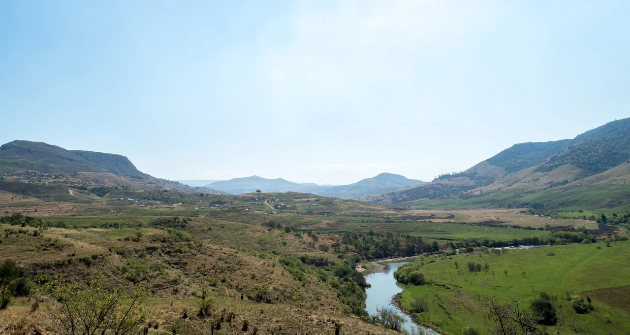 A river winding through a Drakensberg valley with settlements in the distance