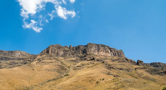 Basalt cliff face of the Drakensberg escarpment against blue sky
